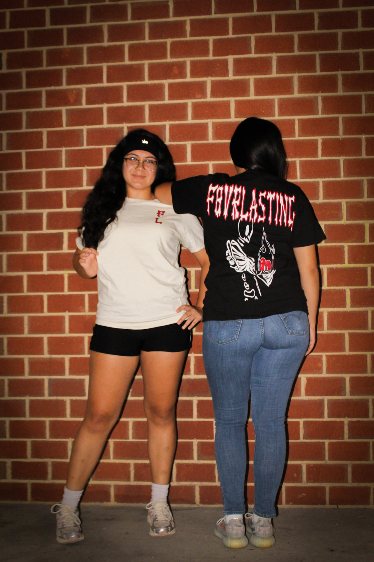 Black and crème F8VRLASTING tees against a brick wall